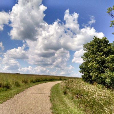 Puffy clouds and trail through grassy hill