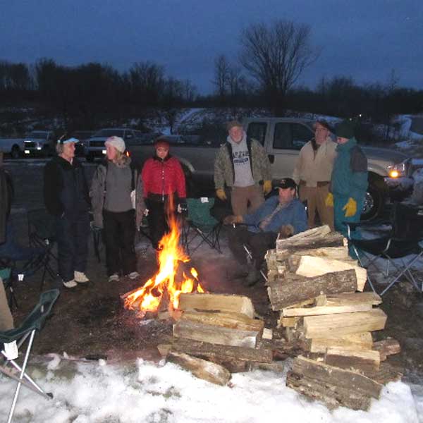 Park visitors gathered around campfire during candlelight ski event