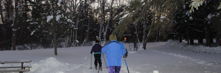 two skiers head down the trail