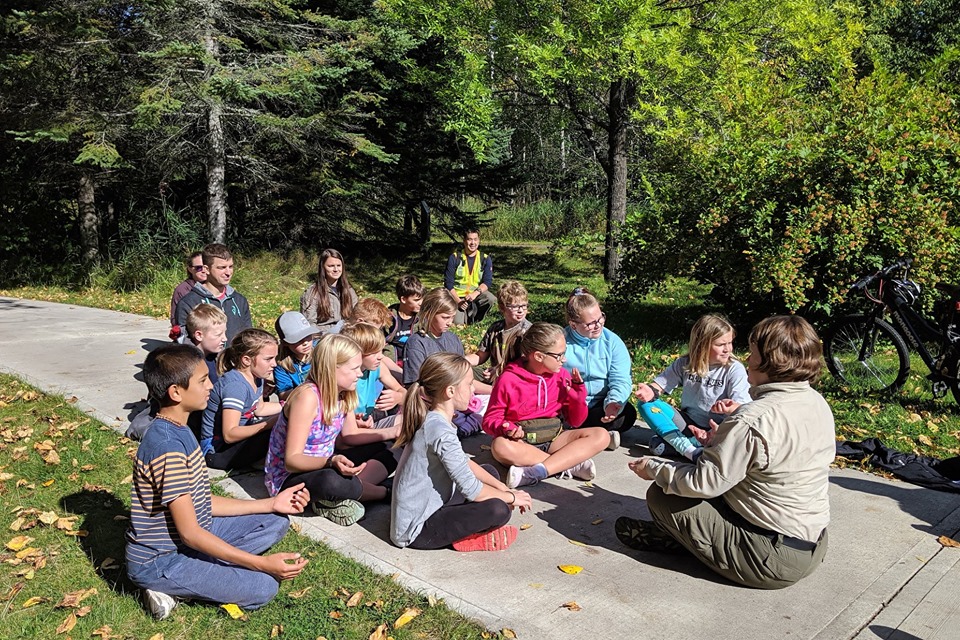 kids sit in meditation with park ranger outside