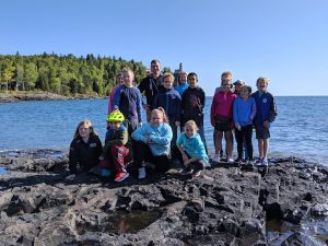 group picture by lake superior with lighthouse in background