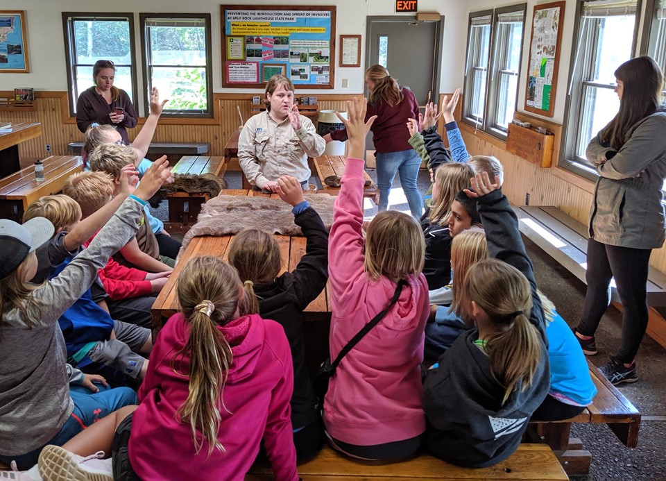 kids raise hand to answer question asked by park ranger