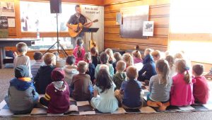 kids sitting on floor in rapt attention to the musician