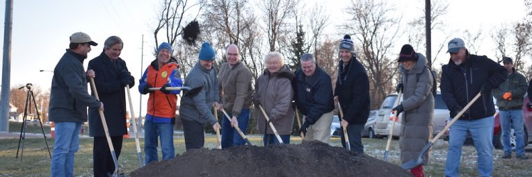 Ten people dig their shovels into a pile of dirt for the ground breaking ceremony