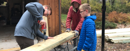 three volunteers building a bench