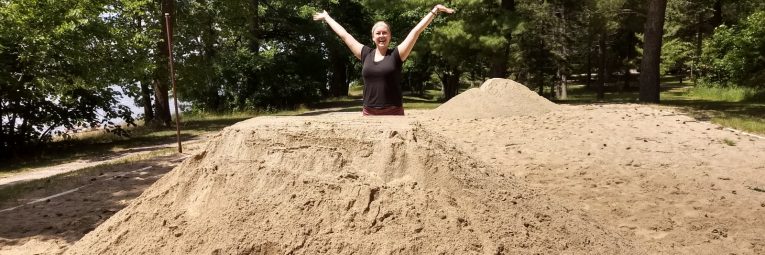 woman stands behind pile of volleyball sand