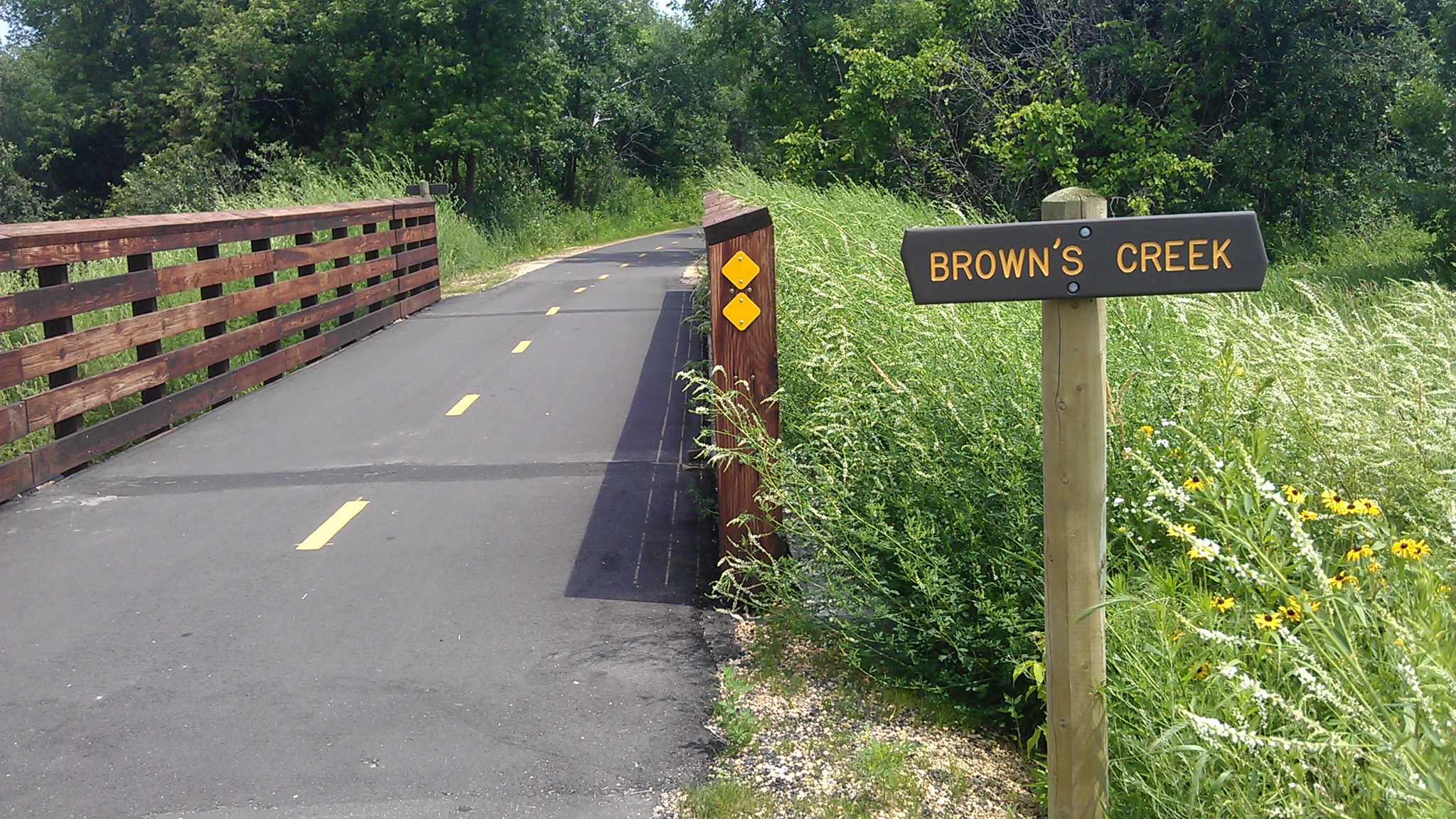 paved trail over bridge with sign