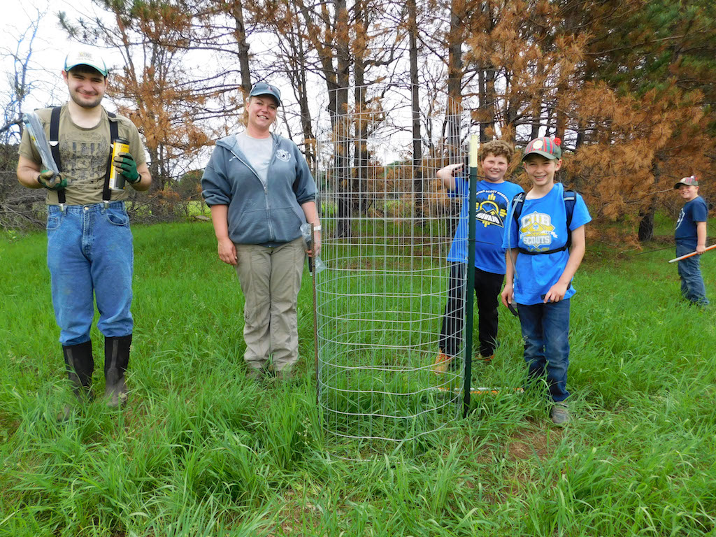 the team poses next to the newly-erected tree cage