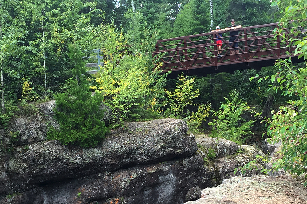 Man and boy looking down from trail bridge at Temperance River State park