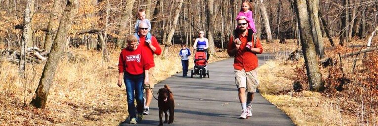 Families walk through the forest on a paved trail