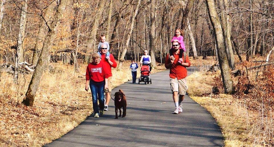Families walk through the forest on a paved trail
