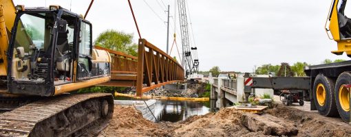 crane installing a trail bridge over a river