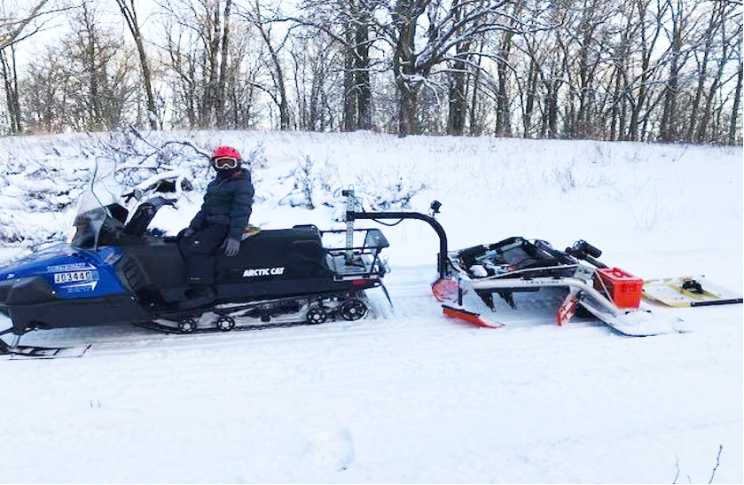 snowmobile pulling a trail groomer