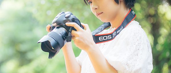 Girl surrounded by greenery with camera