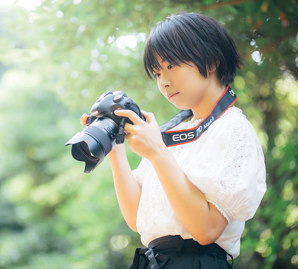 Girl surrounded by greenery with camera