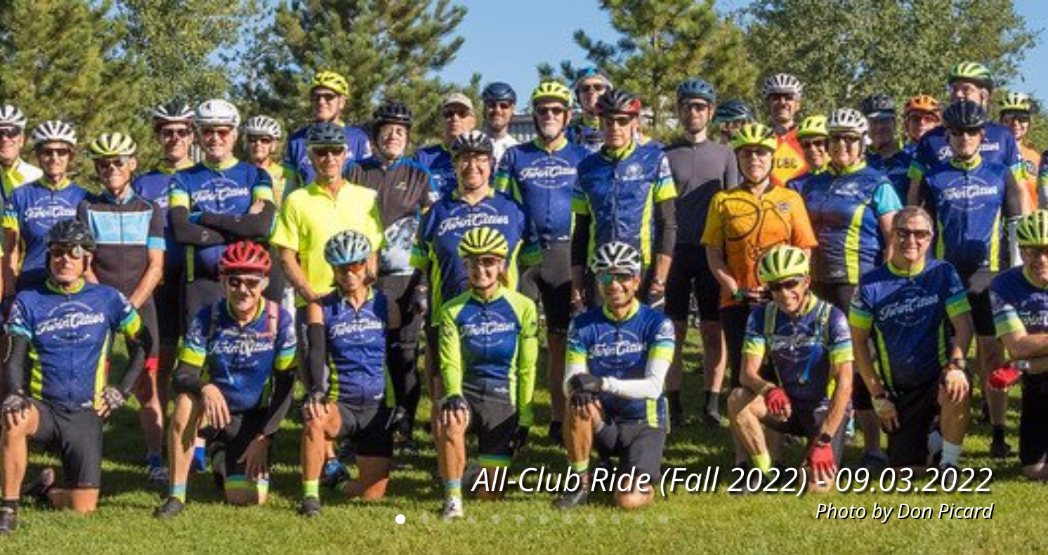 Group of about 30 people posing in bicycle helmets and jerseys.