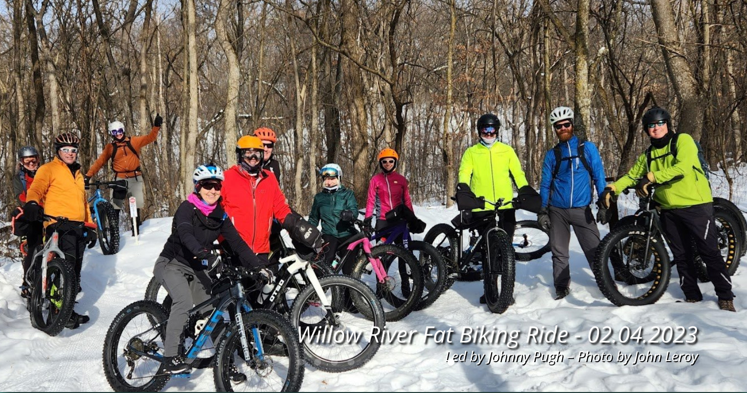 Group of 10 people posing with their bicycles in the snow