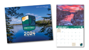 Cover of our 2024 calendar shows a blue lake rimmed by pine trees