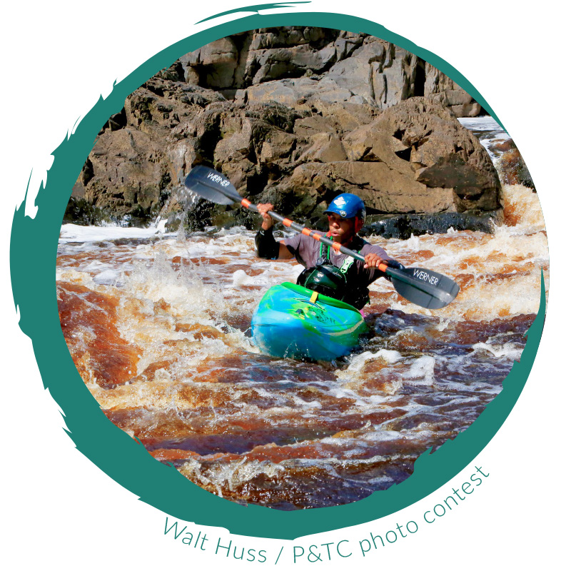 Kayaker on turbulent rapids with large boulders in background