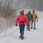 people snowshoeing while it snows