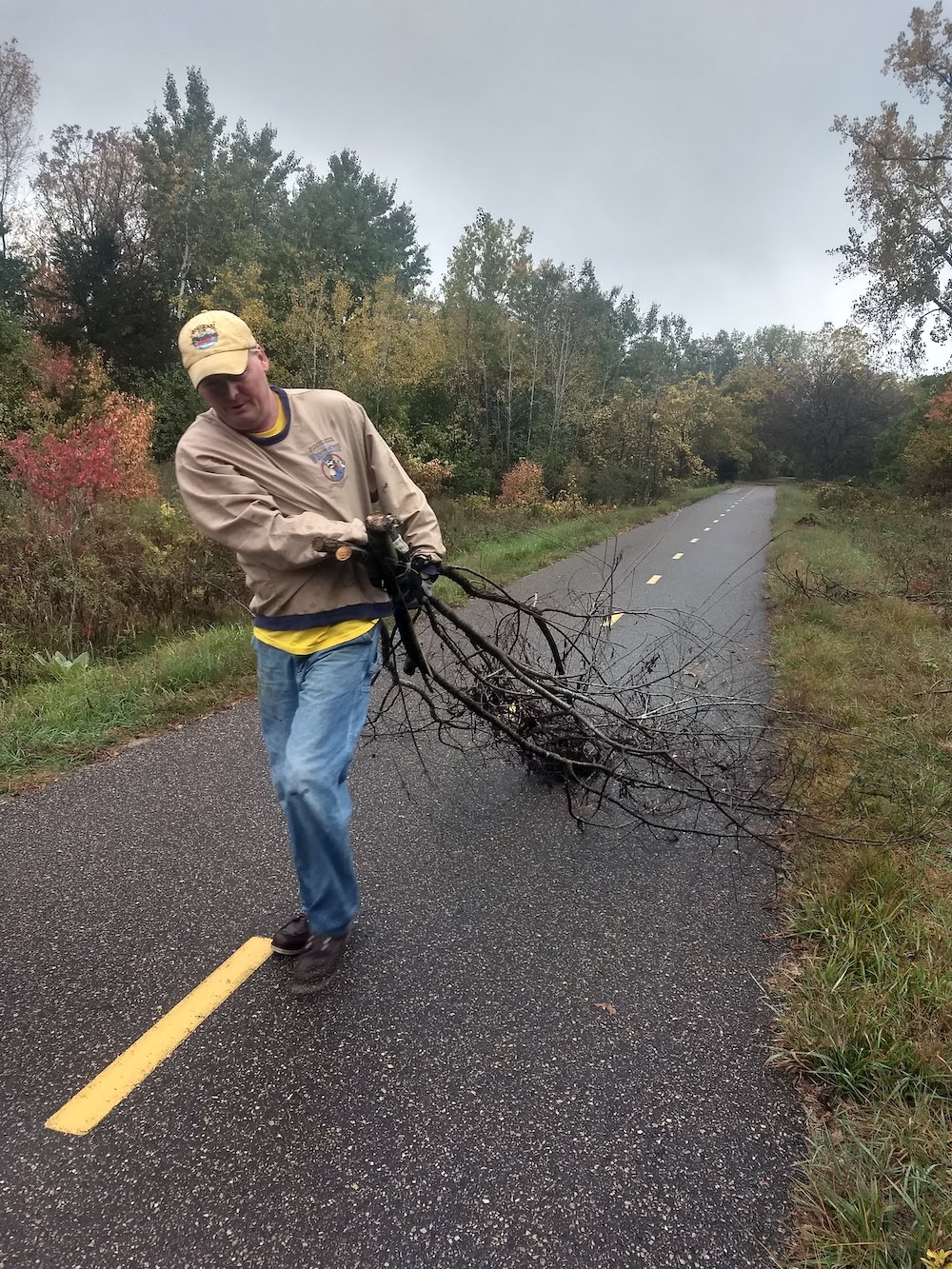 volunteer drags cut buckthorn along trail to pile