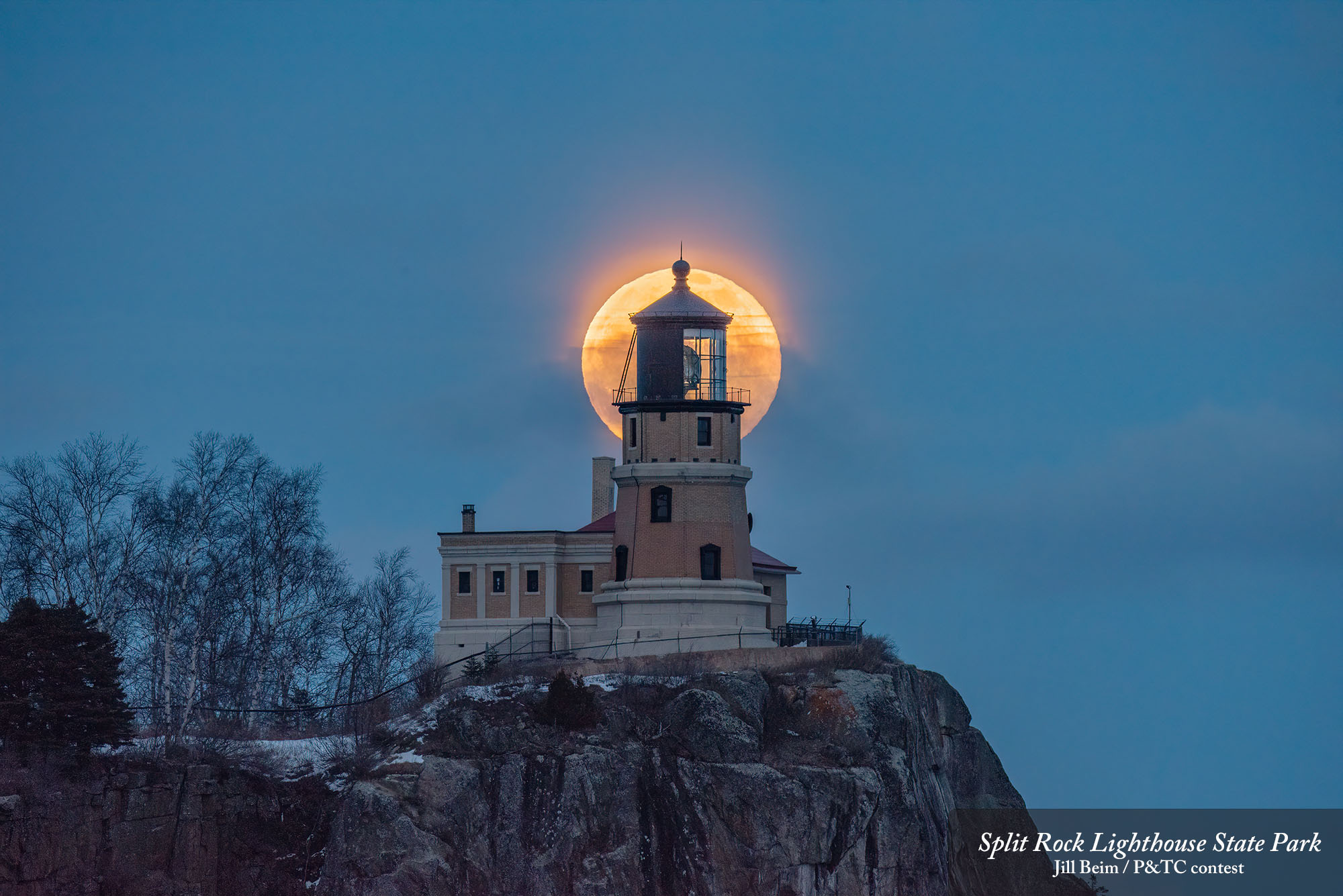 Full moon shining behind a lighthouse
