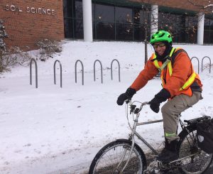 Man on bicycle with helmet, gloves and jacket in snowy landscape