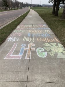 Colorful sidewalk chalk art and saying